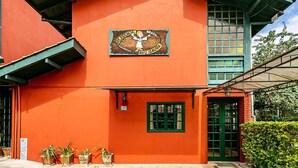 Un edificio de fachada roja, una puerta verde y una ventana con diseño de cuadrícula.