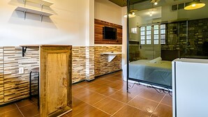 Una cocina moderna con detalles de madera, un televisor integrado y un panel de vidrio que separa la cocina del comedor.