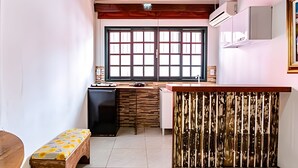Una cocina compacta con techo de madera, una ventana de diseño cuadriculado, un lavamanos y un refrigerador pequeño.