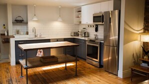 Una cocina moderna con armarios blancos, electrodomésticos de acero inoxidable y una mesa de comedor de madera.