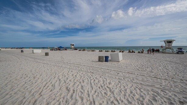 Une plage de sable avec des postes de surveillance pour les sauveteurs, des parasols et des chaises de plage.