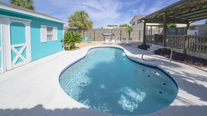 Une piscine à bordures courbes, entourée d’une terrasse en béton.