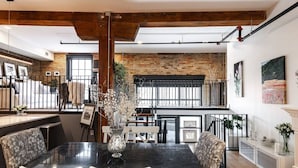 A dining area with a black marble table, white chairs, and a vase with flowers. - Bradshaw Lofts:  La Galleria (Stratford)