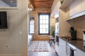 A modern kitchen with a brick wall, a large window, and a small dining area.