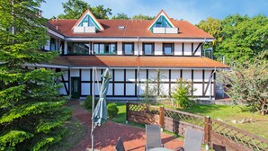 A two-story house with a red-tiled roof, white exterior walls, and green window frames. - Ferienwohnung Karlshagen (Karlshagen (Ostseebad))