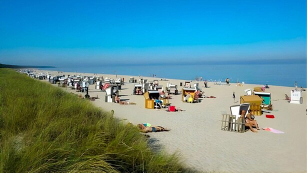 A beach with numerous beach huts and people. - Ferienwohnung Karlshagen (Karlshagen (Ostseebad))