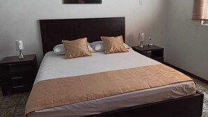 Hotellihuone, jossa on suuri sänky, kaksi yöpöytää ja taulu seinällä.