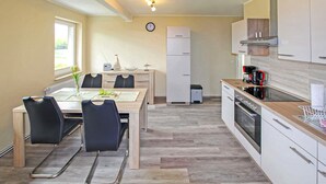A compact kitchen with a dining area, featuring a wooden table, chairs, a built-in oven, and a coffee machine. - Cozy apartment in Mirow with WiFi (Mirow)