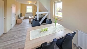 A modern, open-plan living space with a dining area featuring a wooden table, black chairs, and a vase with flowers. - Cozy apartment in Mirow with WiFi (Mirow)