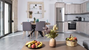 A modern kitchen with a built-in oven, a stainless steel refrigerator, and a dining area with a table and chairs. - 2steps Agia Marina Beach/new Built/no Car Needed/tavernas & Supermarket at 50mt (Agia Marina)