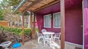 A covered patio with a table and chairs, a blue birdbath, and a wooden pergola.