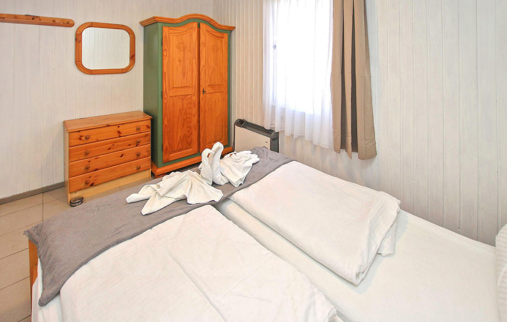 A bedroom with a bed, a wooden dresser, a mirror, and a radiator.