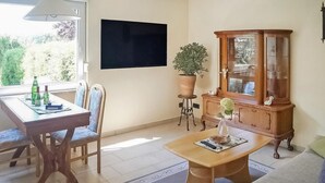 A living room with a dining table, chairs, a sofa, a wooden cabinet, and a potted plant. - Lovely home in Lychen with sauna (Lychen)