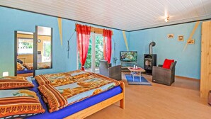 Een gezellige kamer met een bed, een televisie, een open haard en een raam met gordijnen.
