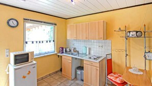 Een compacte keuken met een magnetron, spoelbak en houten kastjes.
