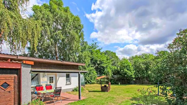 Een huis met een terras, een kleine tuin en een tuinhuis.