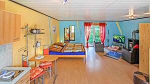 Een compacte kamer met een bed, een eettafeltje, een televisie en een kitchenette.