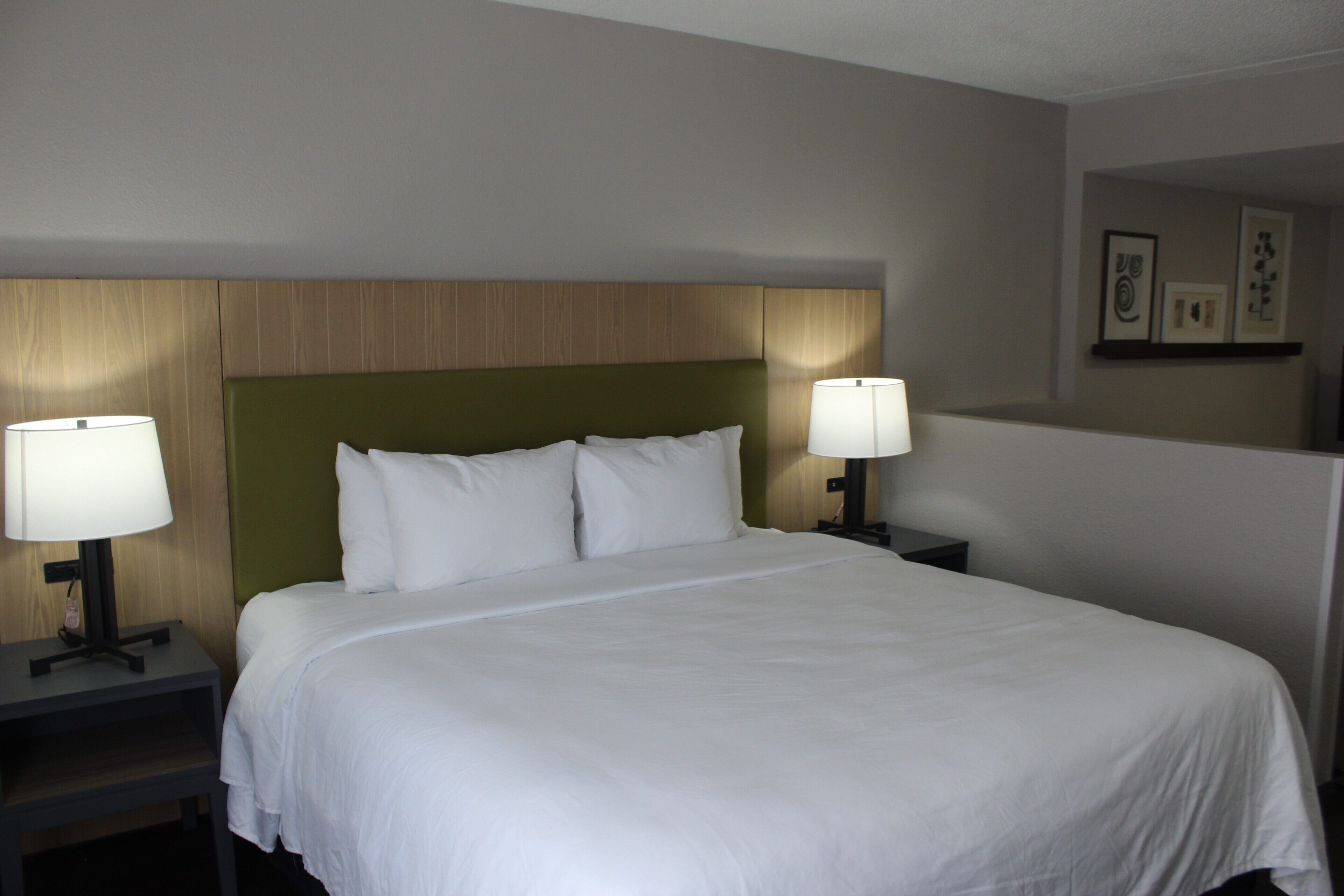 Ein Hotelzimmer mit einem großen Bett, zwei Nachttischlampen und einem Kopfteil mit Holzpaneelen.