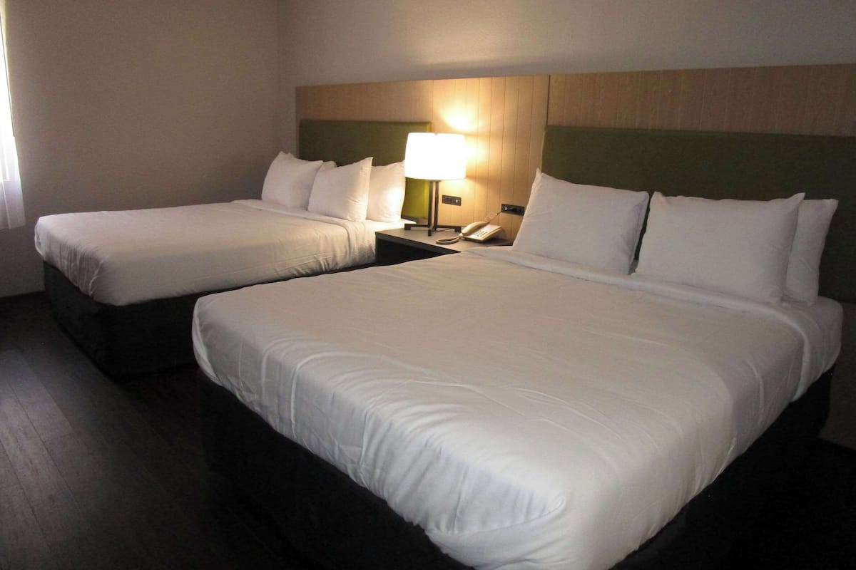 Une chambre d’hôtel avec deux lits, une table de chevet avec une lampe et un téléphone.