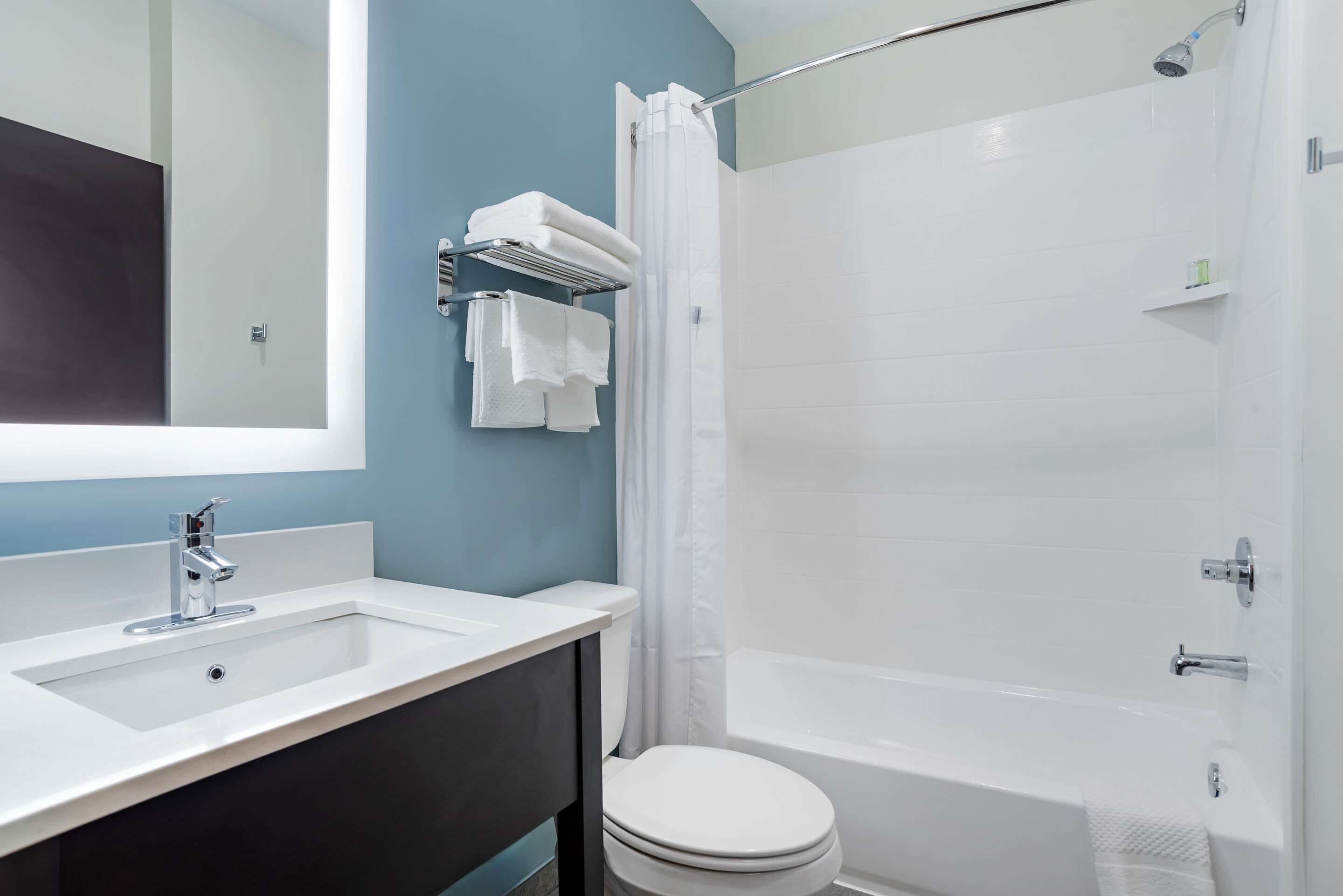 Une salle de bain avec un lavabo blanc, des toilettes et une baignoire.