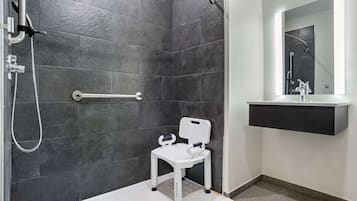 A modern bathroom with a shower, a white toilet, and a mirror above the sink.