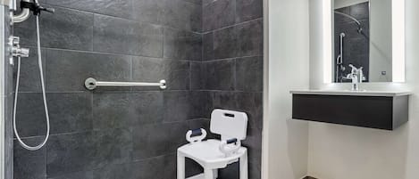 A modern bathroom with a shower, a white toilet, and a mirror above the sink.