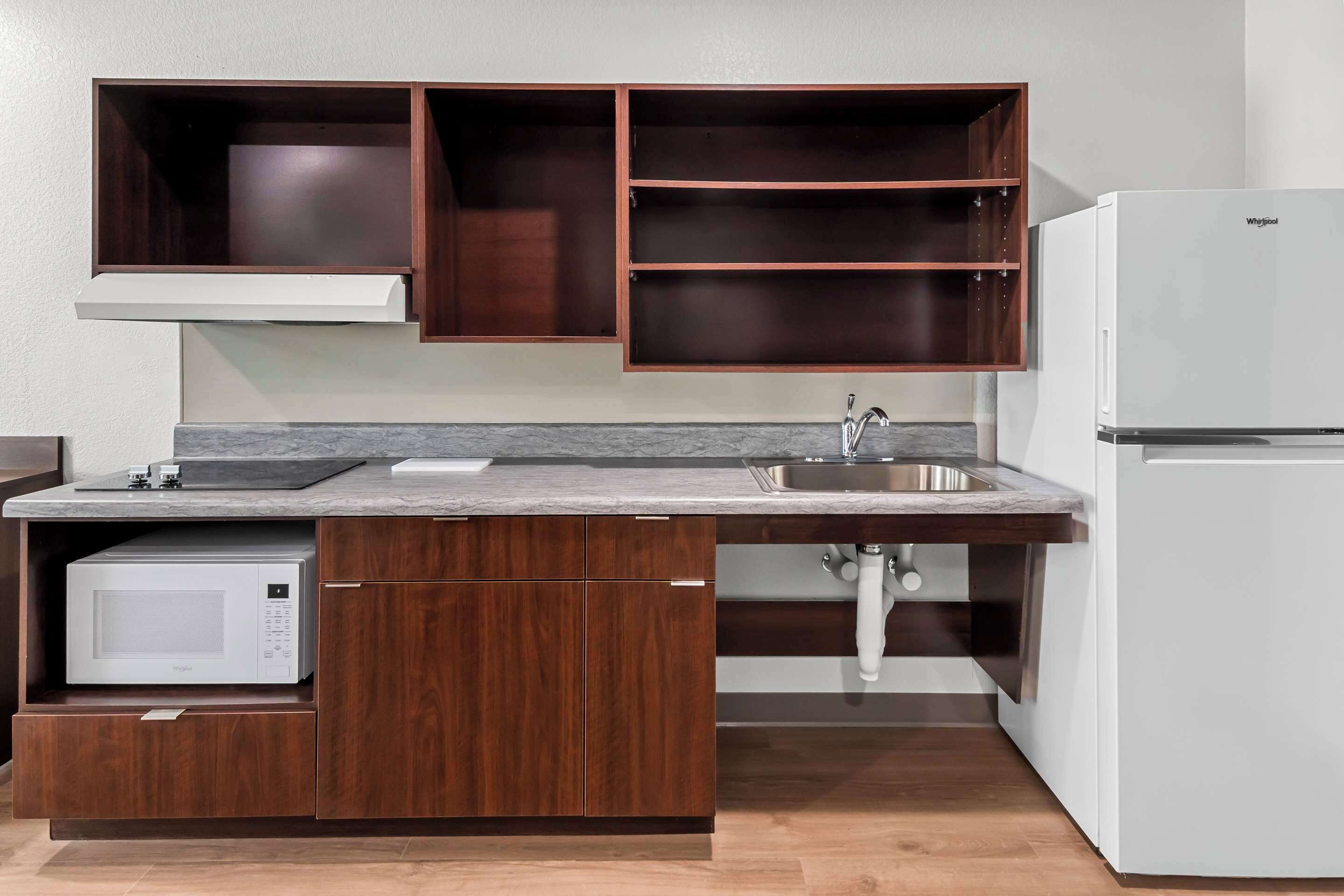 A kitchen with a built-in microwave, a sink, and a white refrigerator.