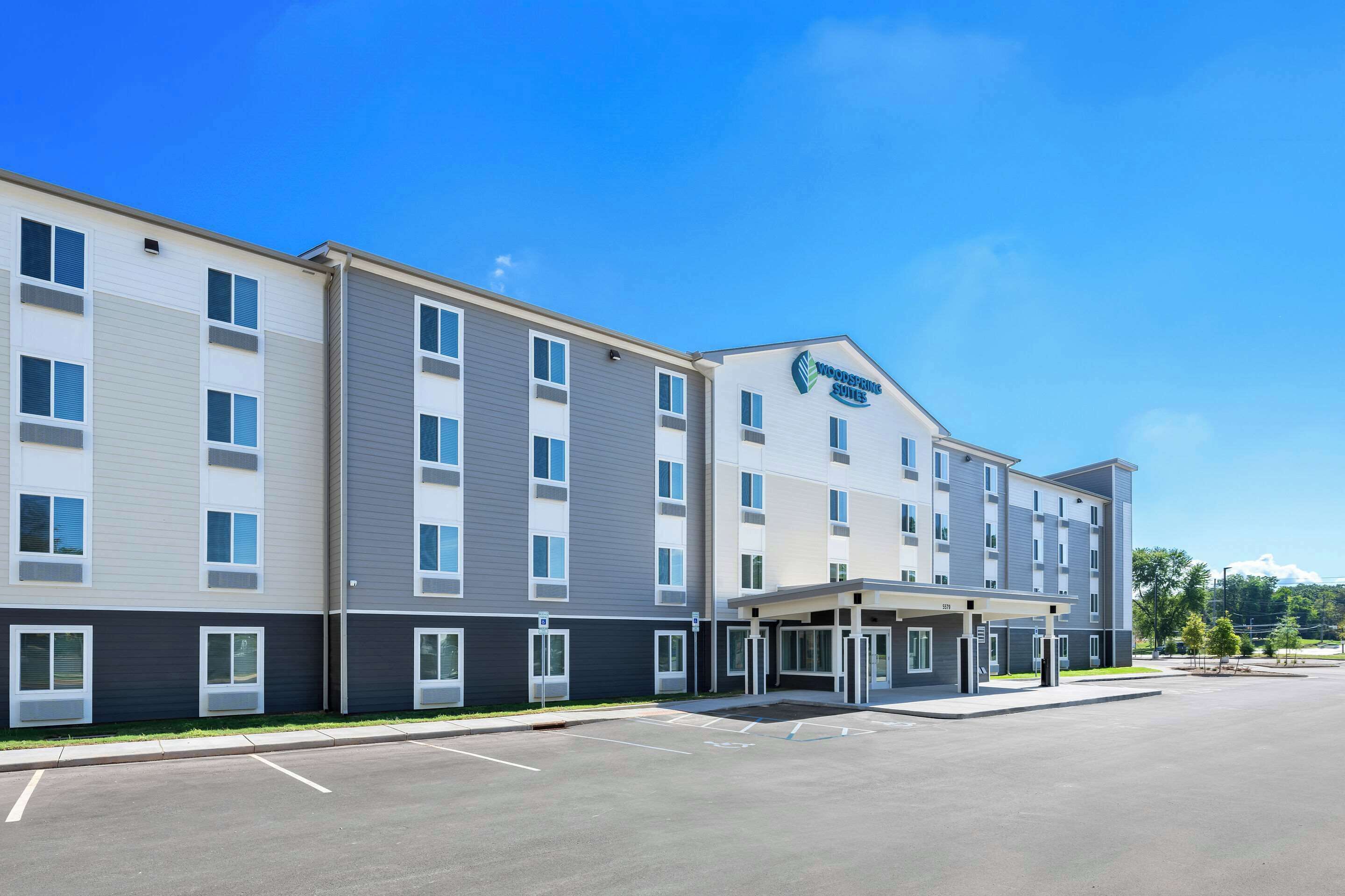A modern hotel with a two-story structure, a covered entrance, and a parking lot.