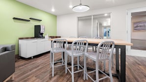 Un espace de bureau moderne comprenant une longue table, plusieurs chaises, un canapé et un meuble de rangement.