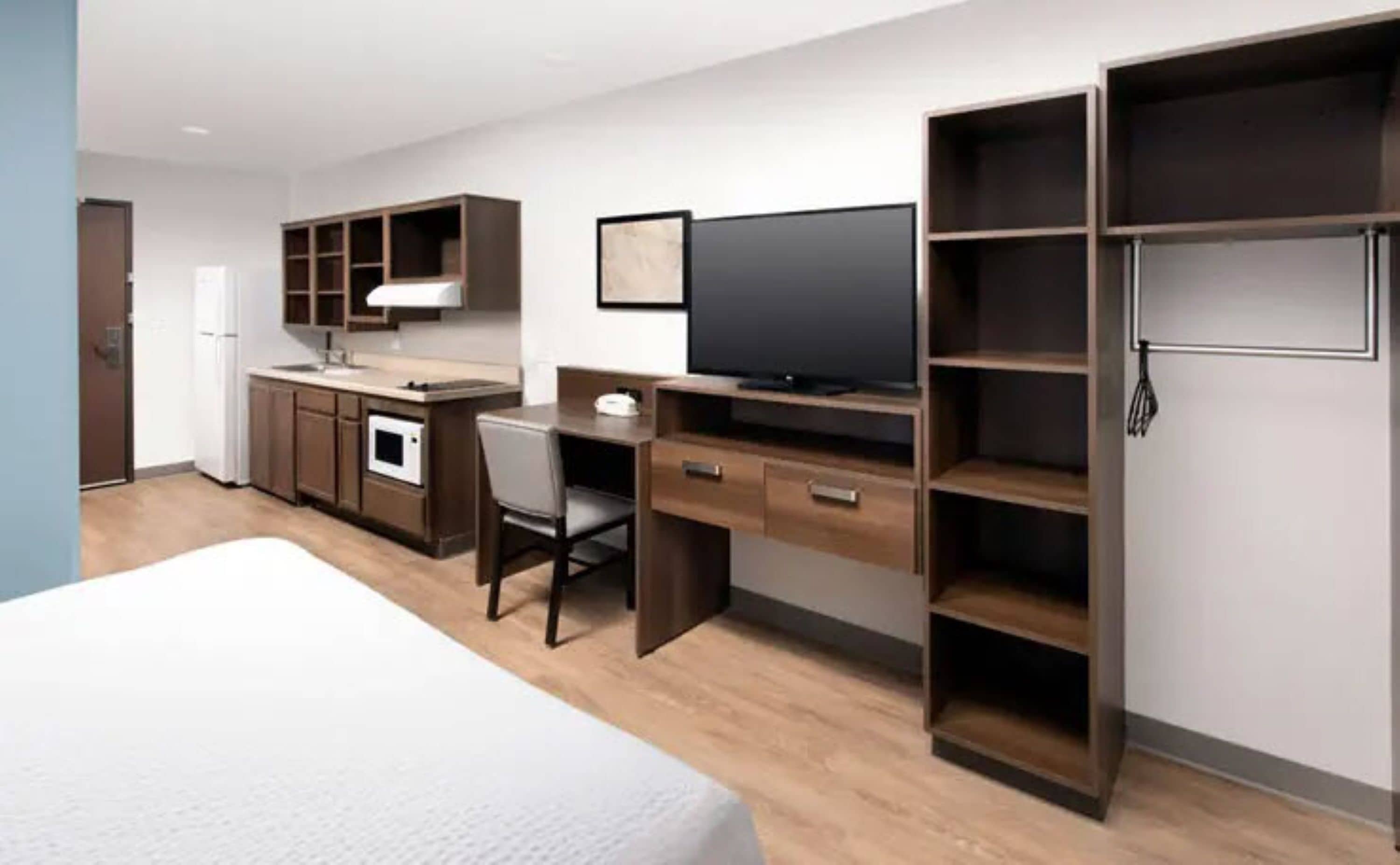 Une chambre d’hôtel moderne équipée d’un lit, d’un bureau, d’une télévision, d’un four à micro-ondes et d’une armoire.