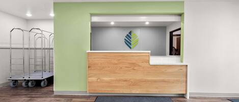 A reception desk with a green accent wall, a logo, and a cart with wheels.