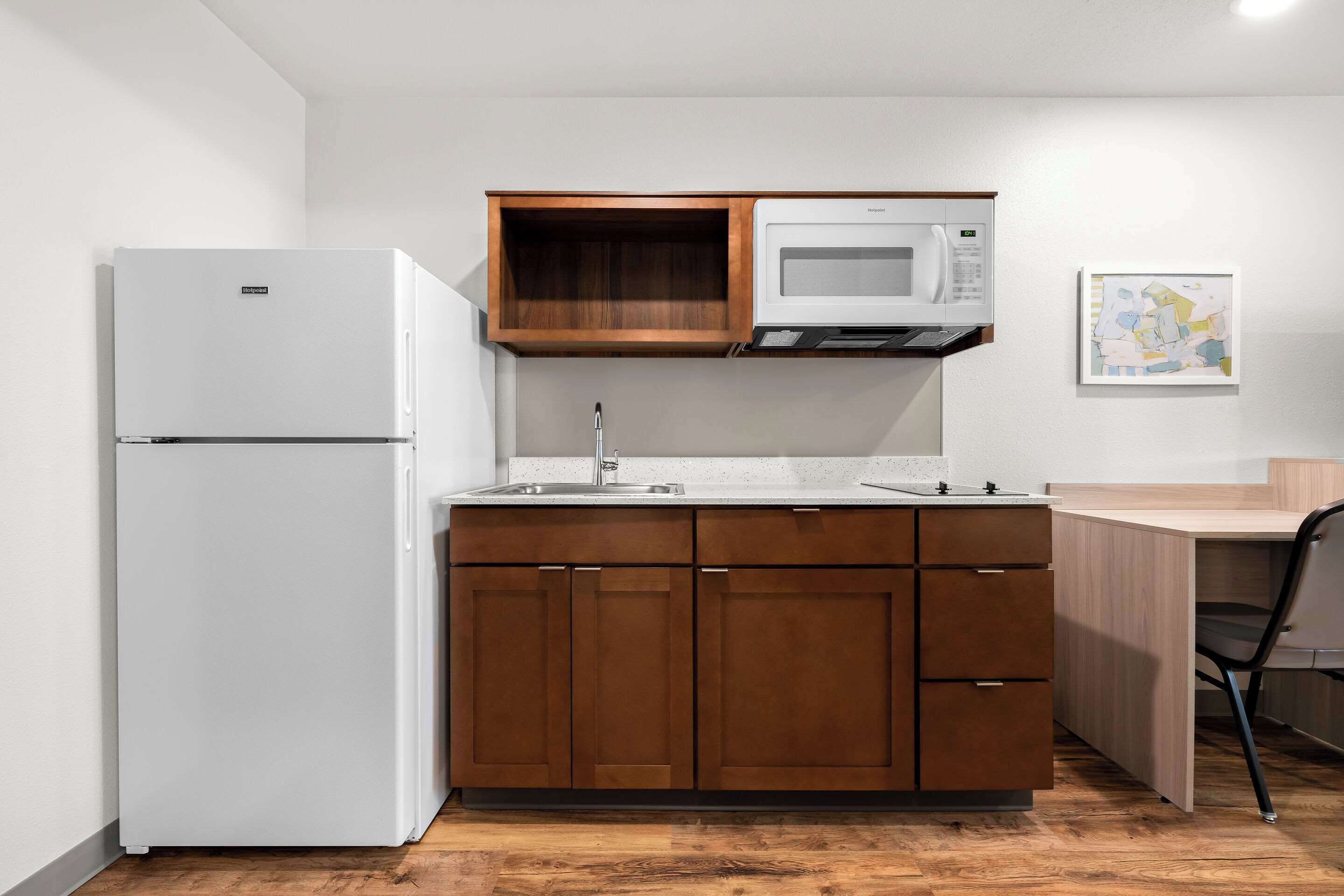 A compact kitchen with a white refrigerator, a microwave, and wooden cabinets.