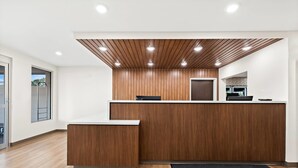 A reception desk with a wooden finish, a flat-screen TV, and a modern light fixture.