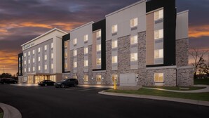 A modern hotel with a stone facade, multiple floors, and a parking lot.