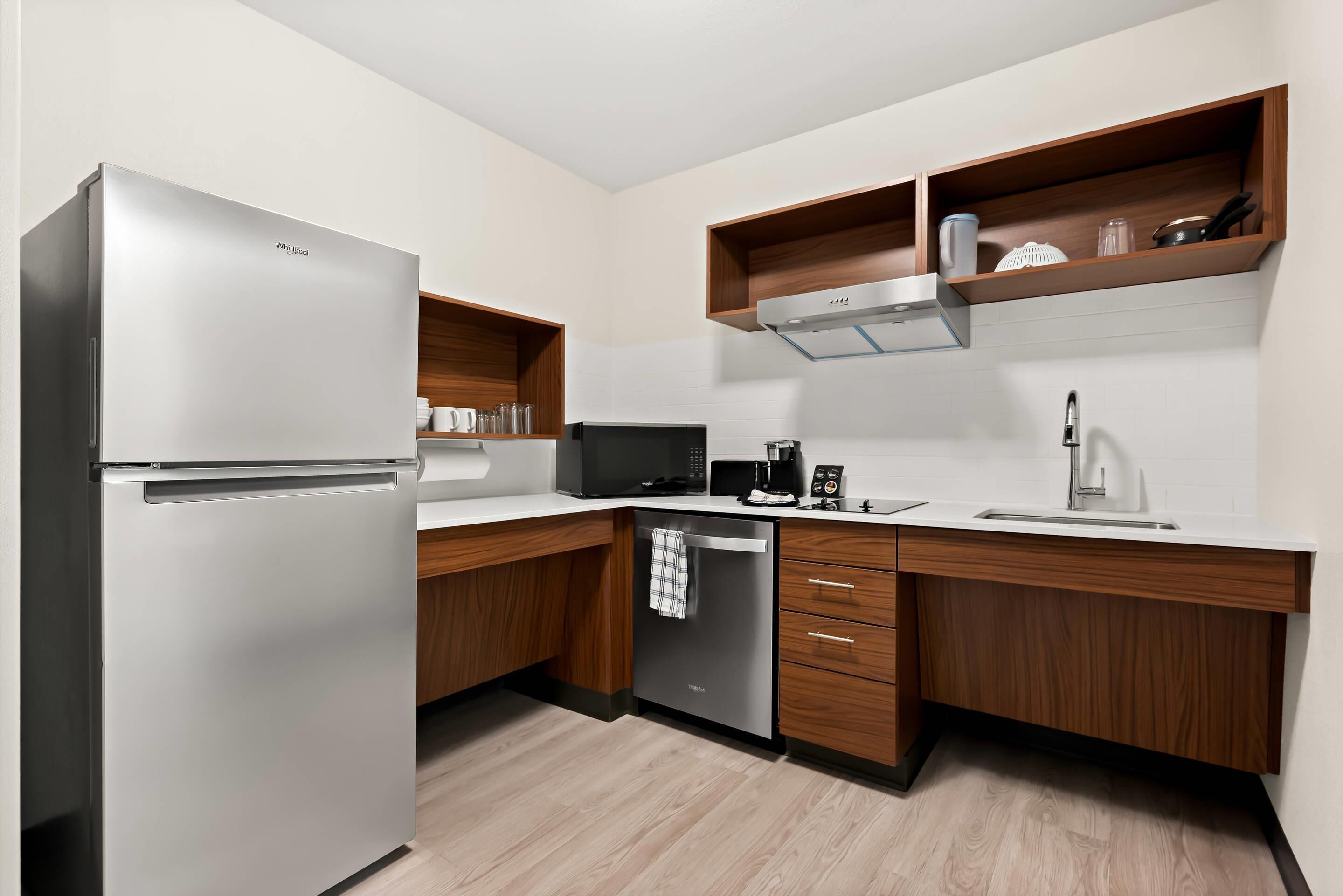 Una cocina moderna con un refrigerador de acero inoxidable, un microondas, una cafetera y armarios de madera.