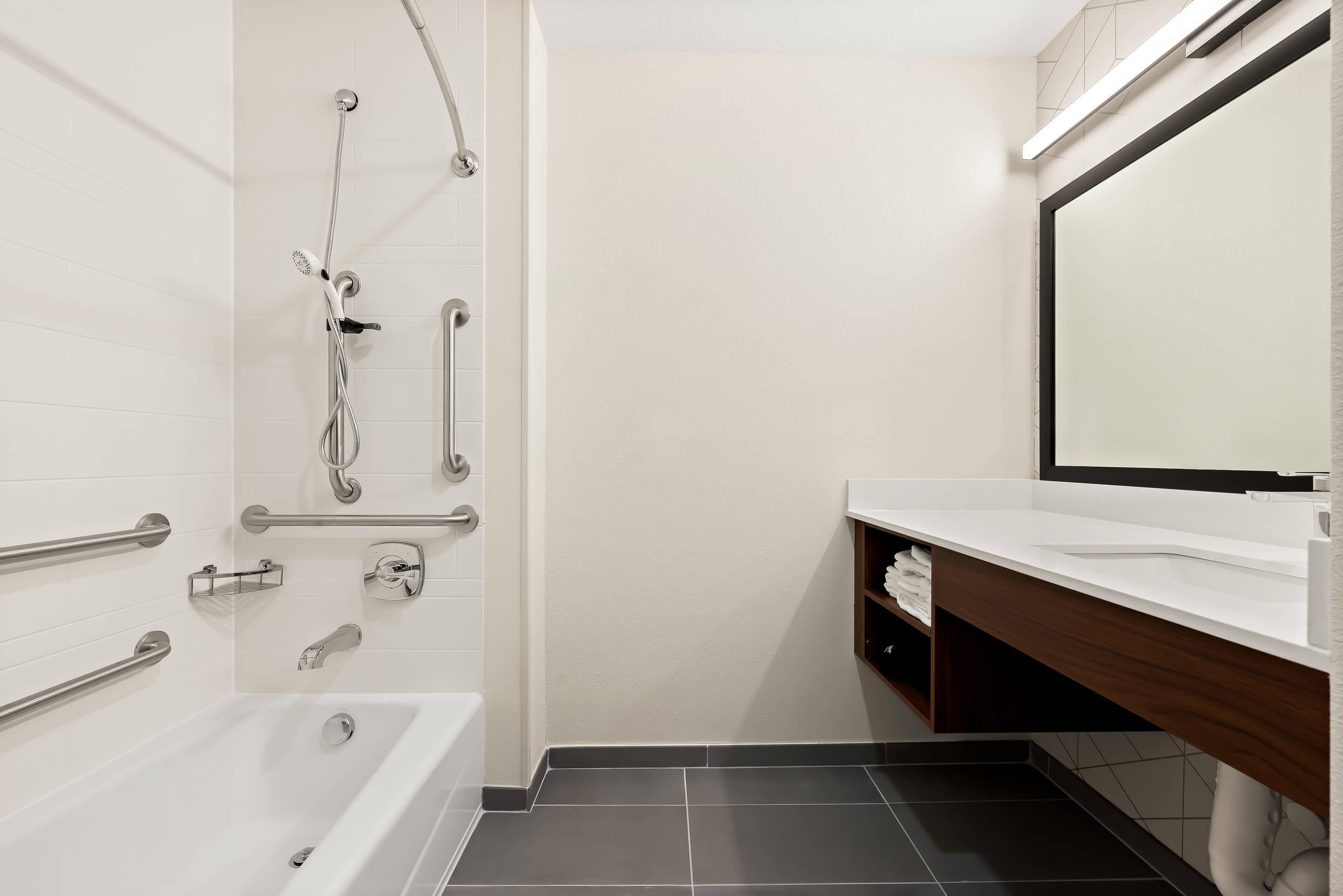 A modern bathroom with a bathtub, shower, and vanity.
