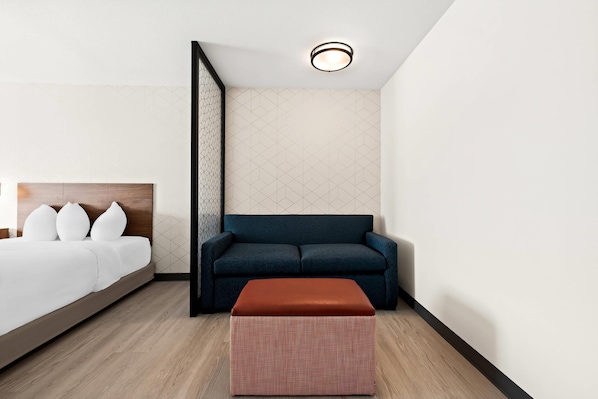 Une chambre d’hôtel moderne avec un lit, un canapé bleu foncé et un plancher en bois.