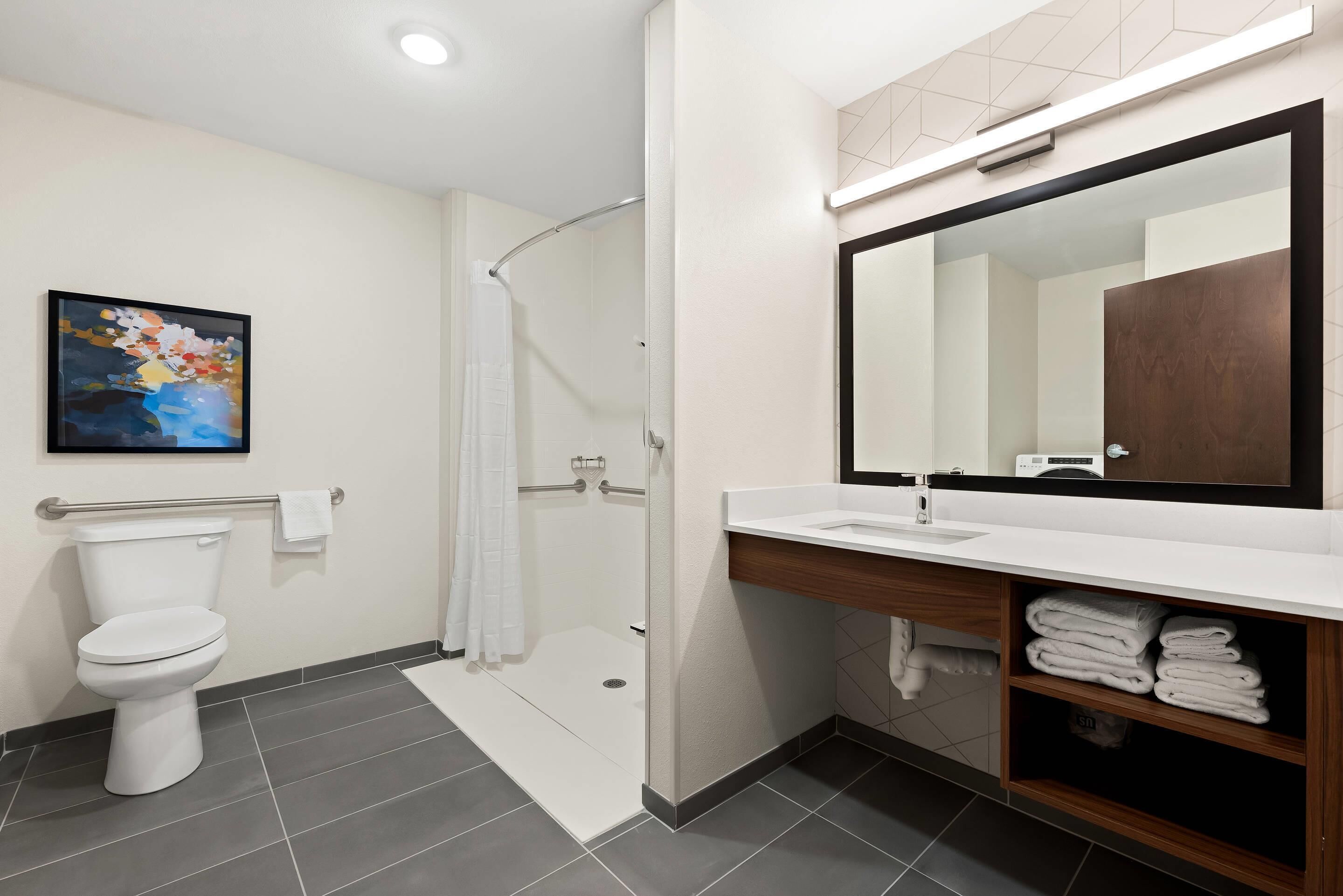 A modern bathroom with a toilet, shower, and sink.