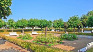 Un parc doté de bancs, d’une statue et de parterres de fleurs bien entretenus.