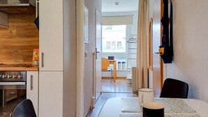 Une cuisine compacte comprenant un fourneau, des placards et un coin repas avec une table et des chaises.