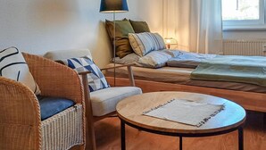 Une pièce confortable avec un lit, une chaise, une petite table et une lampe.