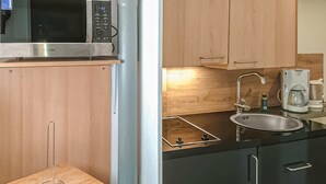 Eine kompakte Küche mit Mikrowelle, Spüle, Kaffeemaschine und einer kleinen Arbeitsfläche.