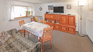 Ein gemütlicher Wohnbereich mit Esstisch, Stühlen, einer Couch, einem Fernseher und einem Schrank.