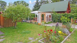 Ein Garten mit einer kleinen Ziegelstruktur, einem Holzzaun und verschiedenen Pflanzen und Blumen.