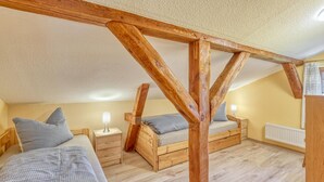 Una camera da letto con due letti in legno, un comodino con una lampada e un termosifone.