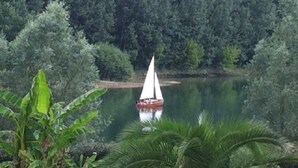 A sailboat on a calm lake surrounded by dense greenery. - Studio 3 Personnes Dans Environnement de Charme (Caudrot)