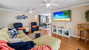 A living room with a sofa, chairs, a TV, and a dining area in the background. - Relaxing 2Bd, 2Ba home in Fort Myers,  close to the beach! Sleeps 6 (Fort Myers)