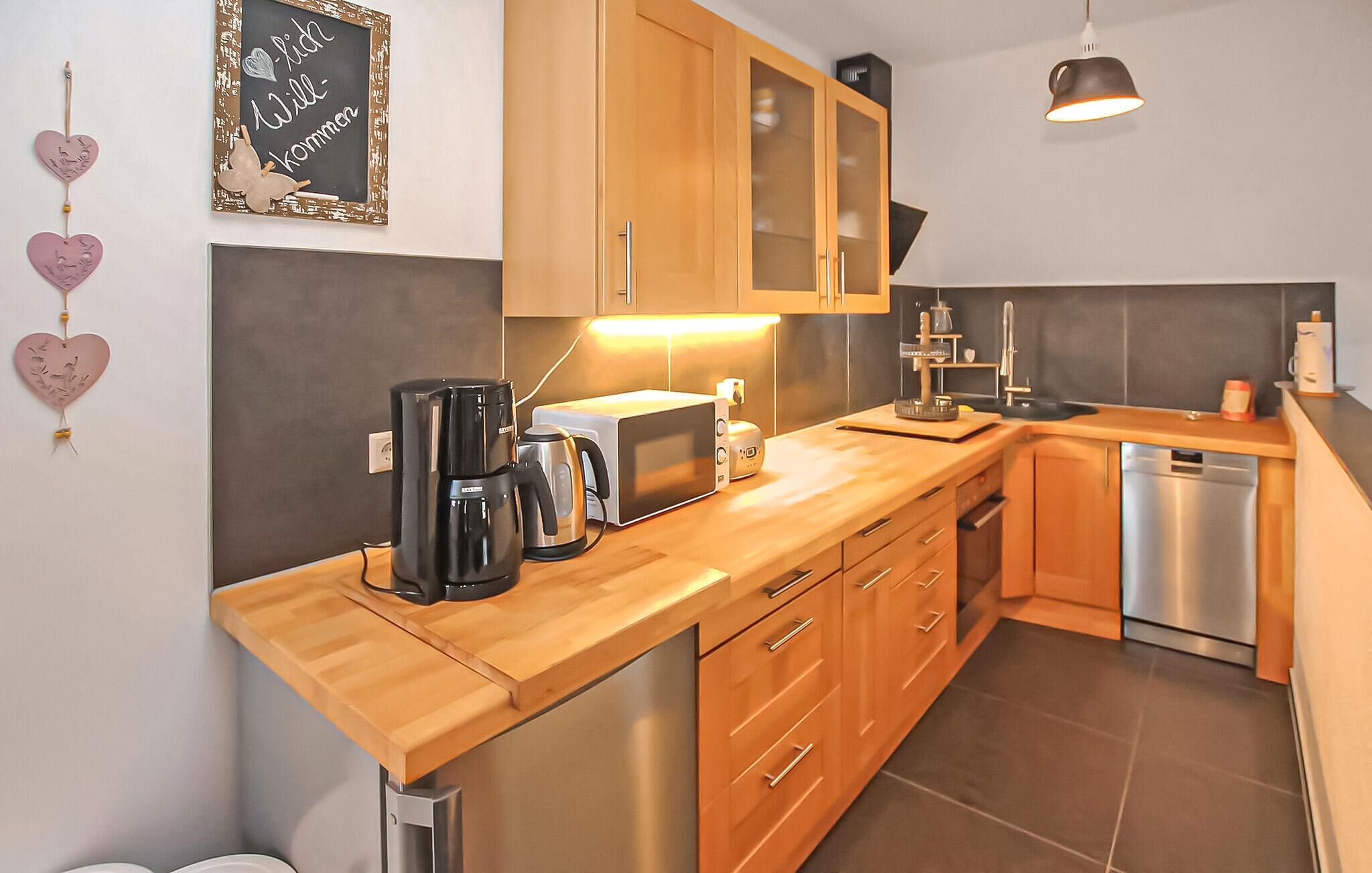 A modern kitchen with wooden cabinets, a coffee maker, a toaster, and a dishwasher.
