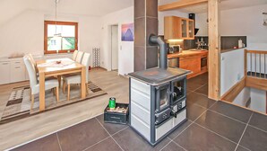 A compact kitchen with a stove, wooden cabinets, and a dining area with a table and chairs. - Ferienwohnung Woldegk (Woldegk)