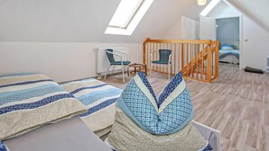 A bedroom with a sloped ceiling, a skylight, a wooden staircase, and a view of a bedroom in the adjacent room. - Ferienwohnung Woldegk (Woldegk)
